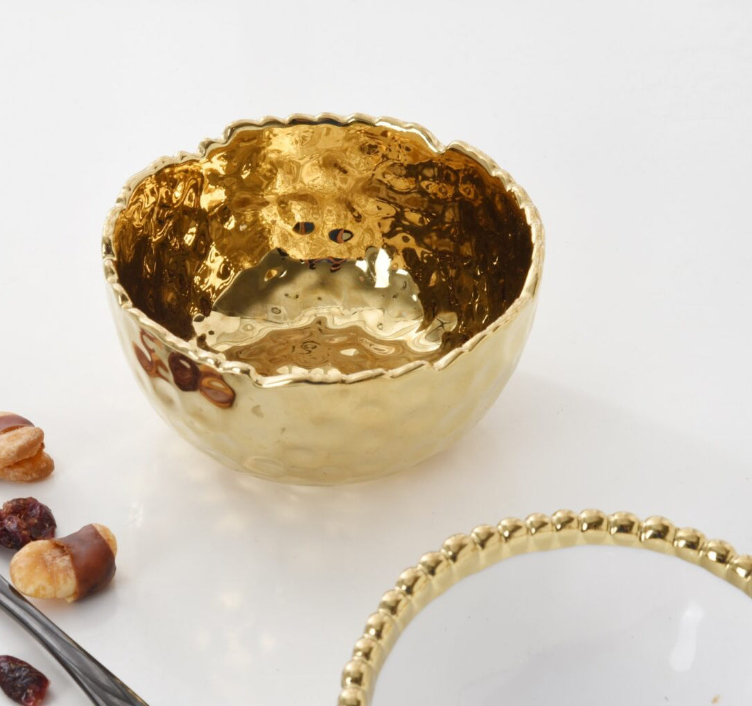 Gold decorative bowl on a white surface with dried fruits and a spoon.