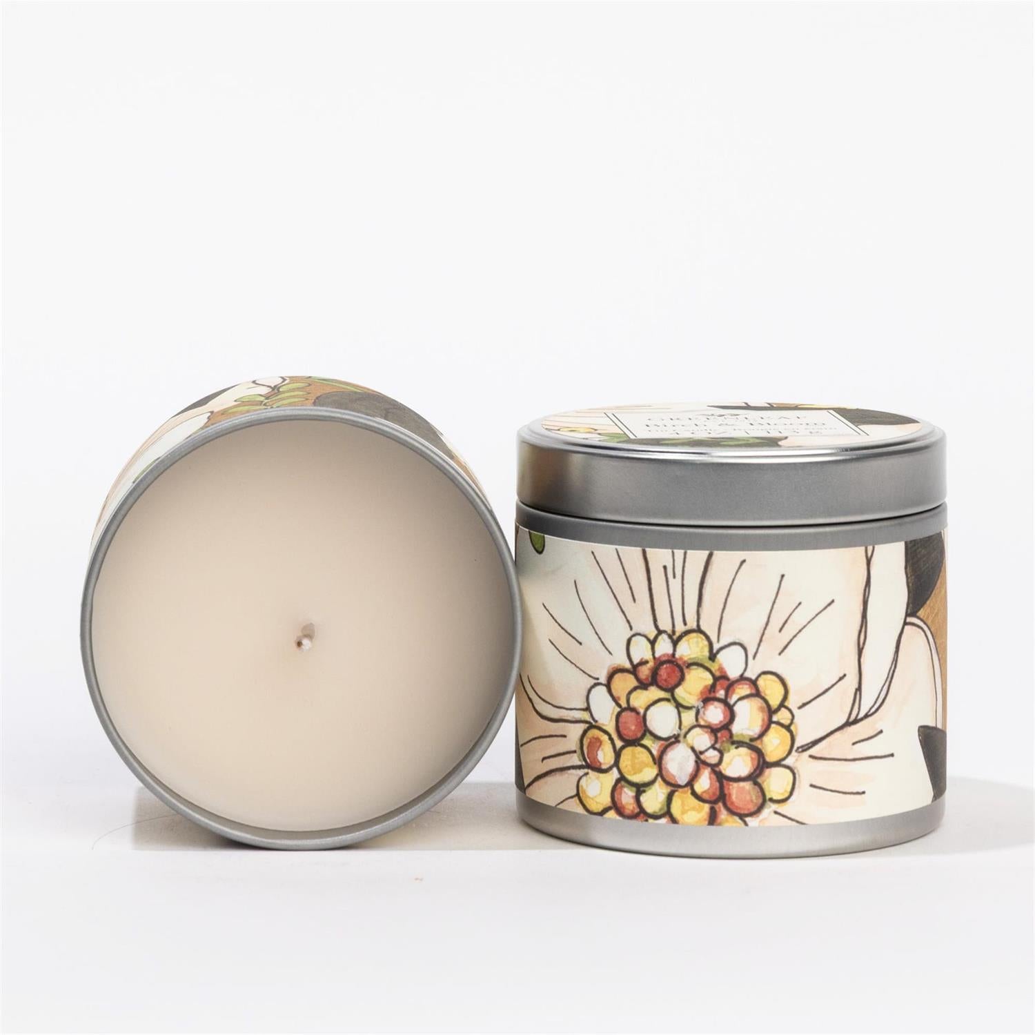 Candle in a decorative tin with a floral design on a white background