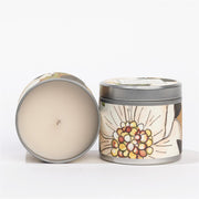 Candle in a decorative tin with a floral design on a white background