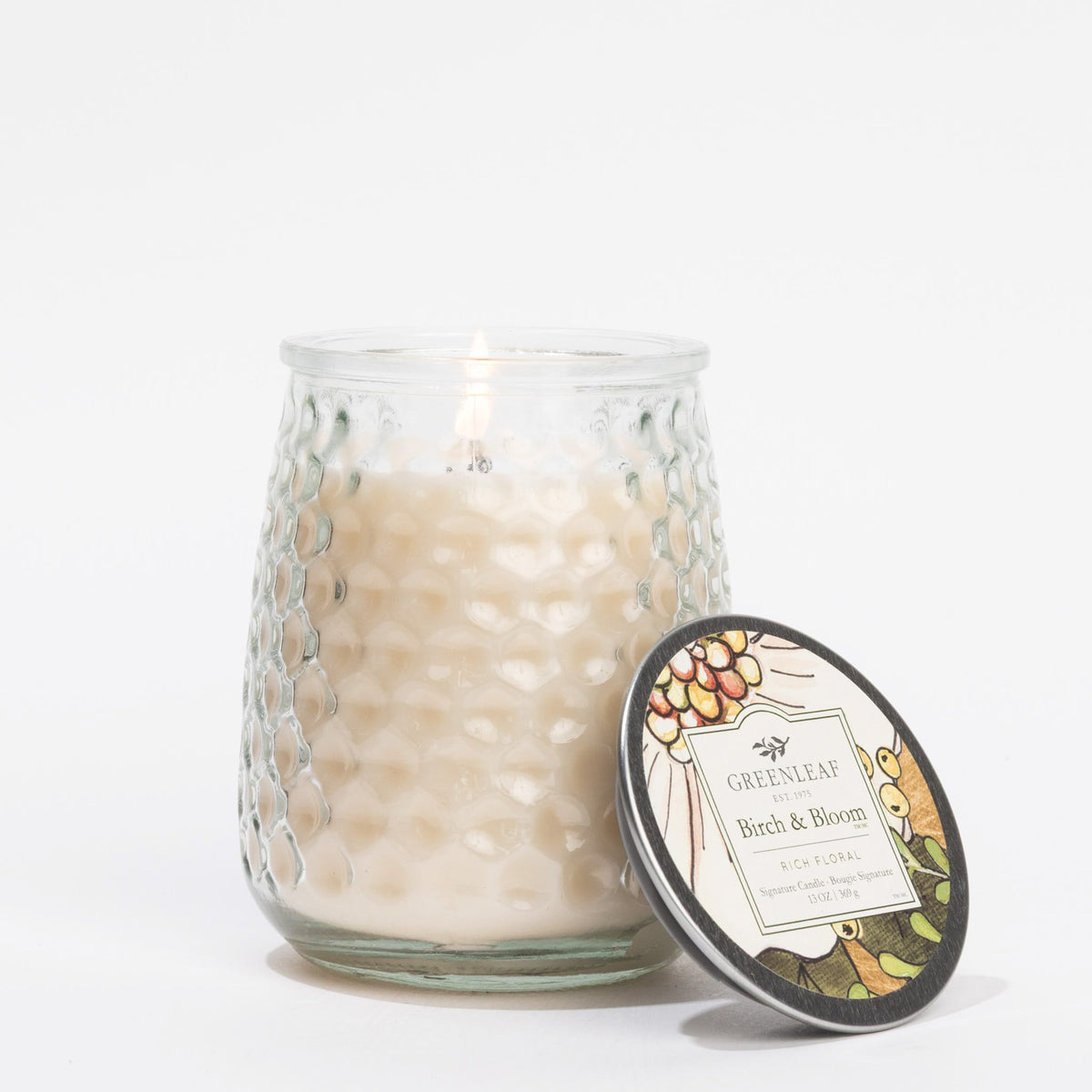 Glass candle with decorative label on a white background