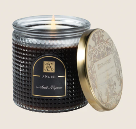 Candle in a textured jar with a decorative lid on a beige background