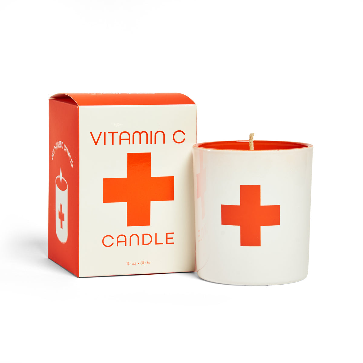 Vitamin C candle with red cross design next to its packaging on a white background