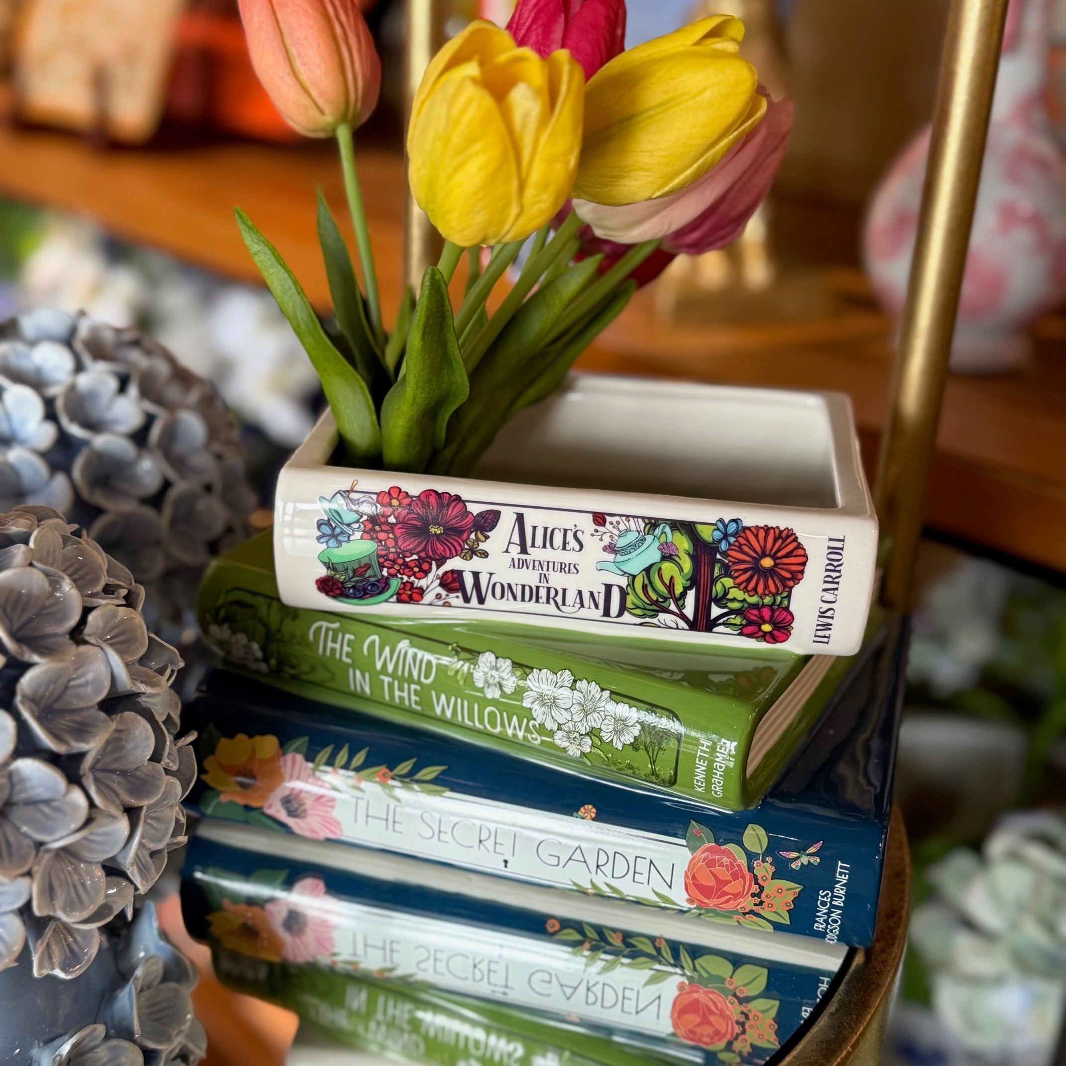 Stack of books with a decorative vase containing tulips on top