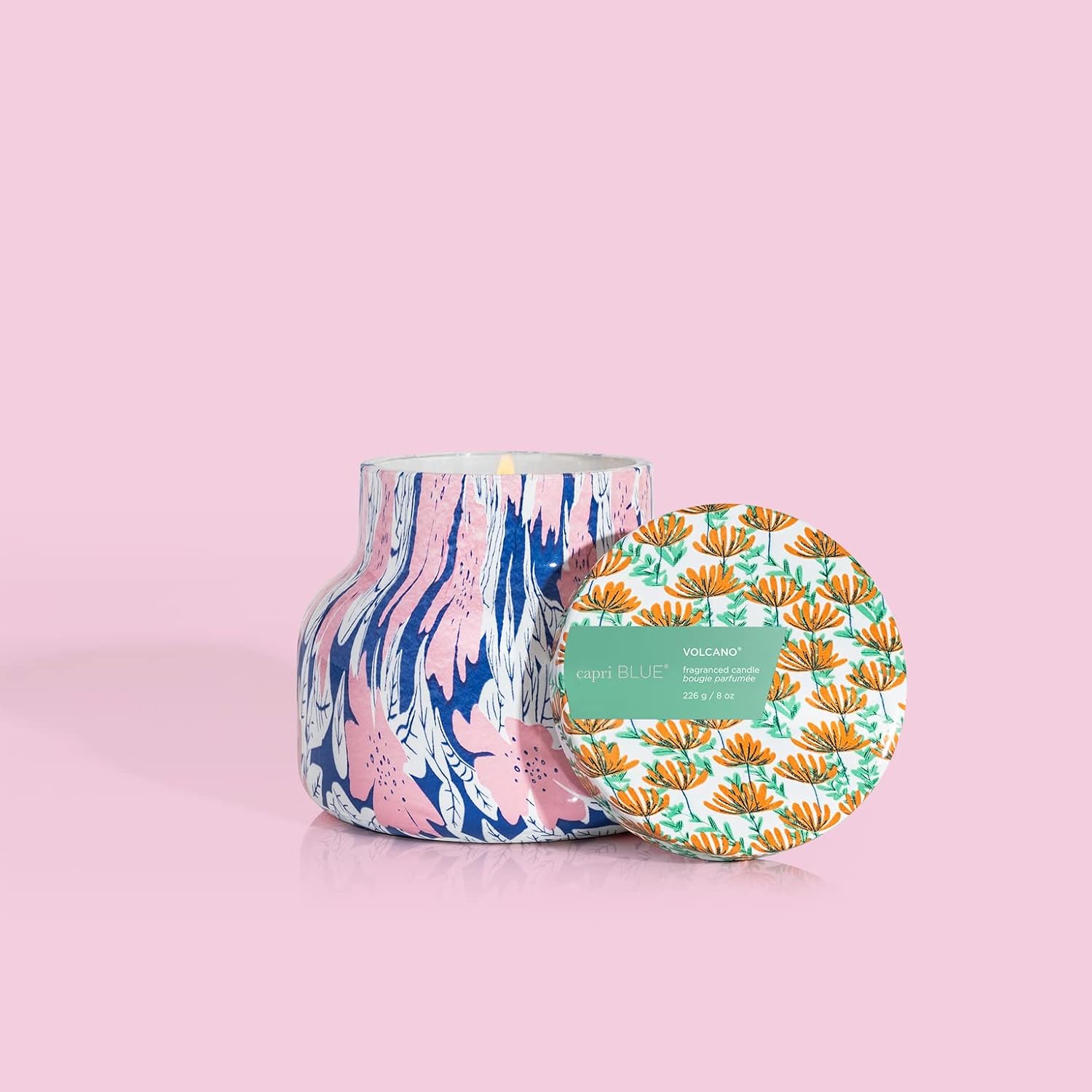 A multicolored floral-patterned candle in an 8oz opened petite jar on a pink background.