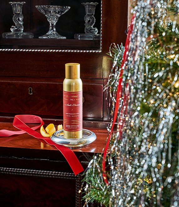 Decorative bottle with gold cap and red label on a wooden surface next to a Christmas tree.