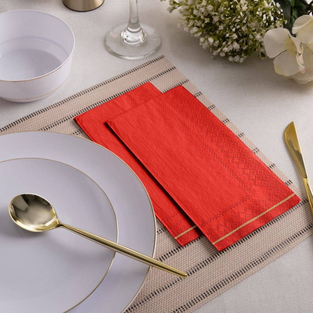 Dining table setting with red napkin, white plate, gold spoon, and floral decor.