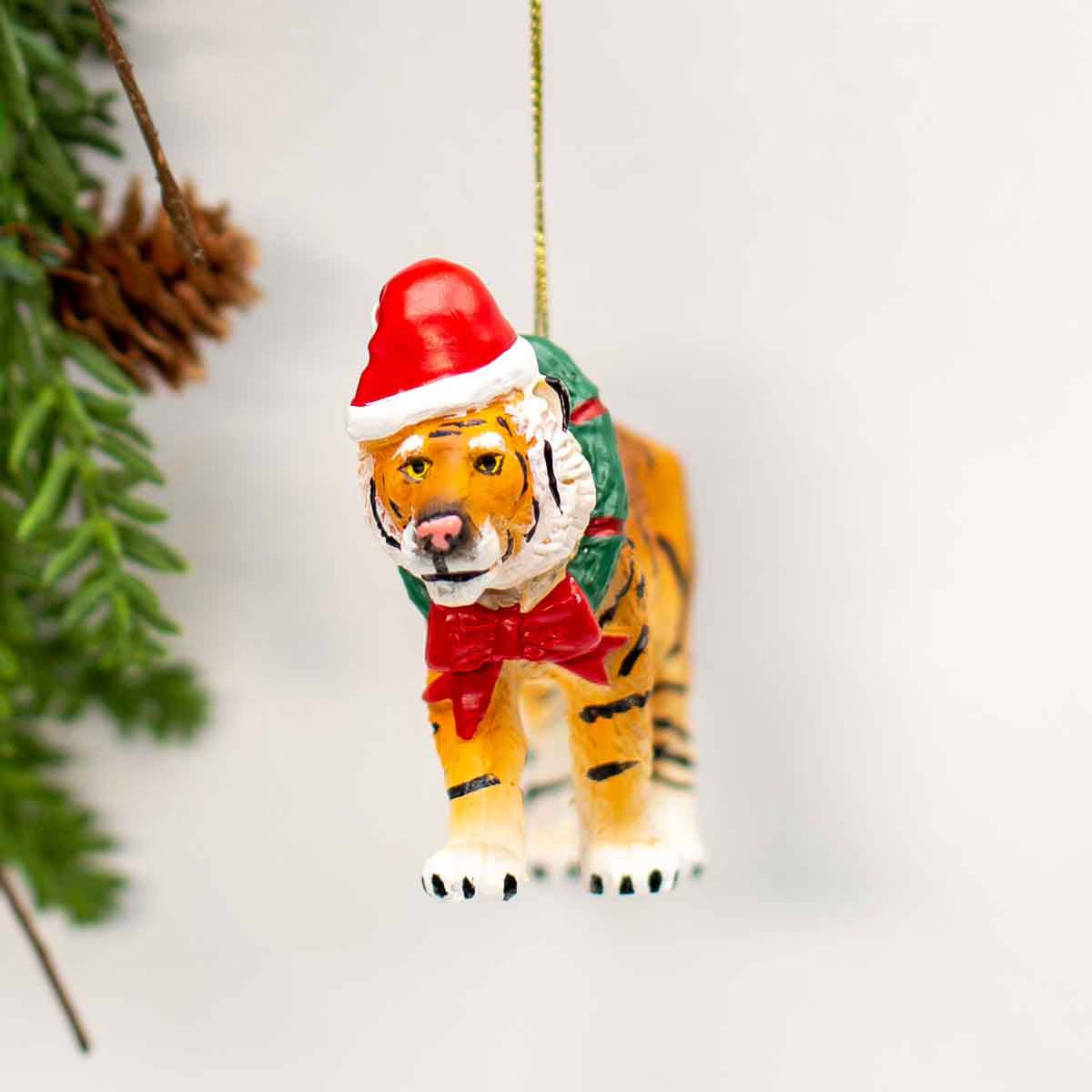 Tiger Christmas ornament wearing a Santa hat and green coat on a white background
