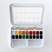 watercolor paint box with 18 colors and a paint brush on white background
