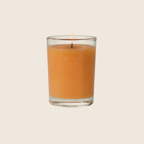 Orange candle in a glass container on a beige background