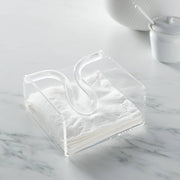 Huang Acrylic brand Clear acrylic square cocktail napkin holder with bow rod filled with white napkins placed on a light marble surface with softly blurred white ceramic dishes in the background.