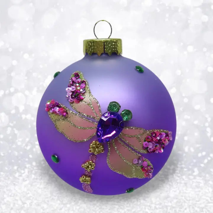 Decorative purple ornament with a dragonfly design on a white background