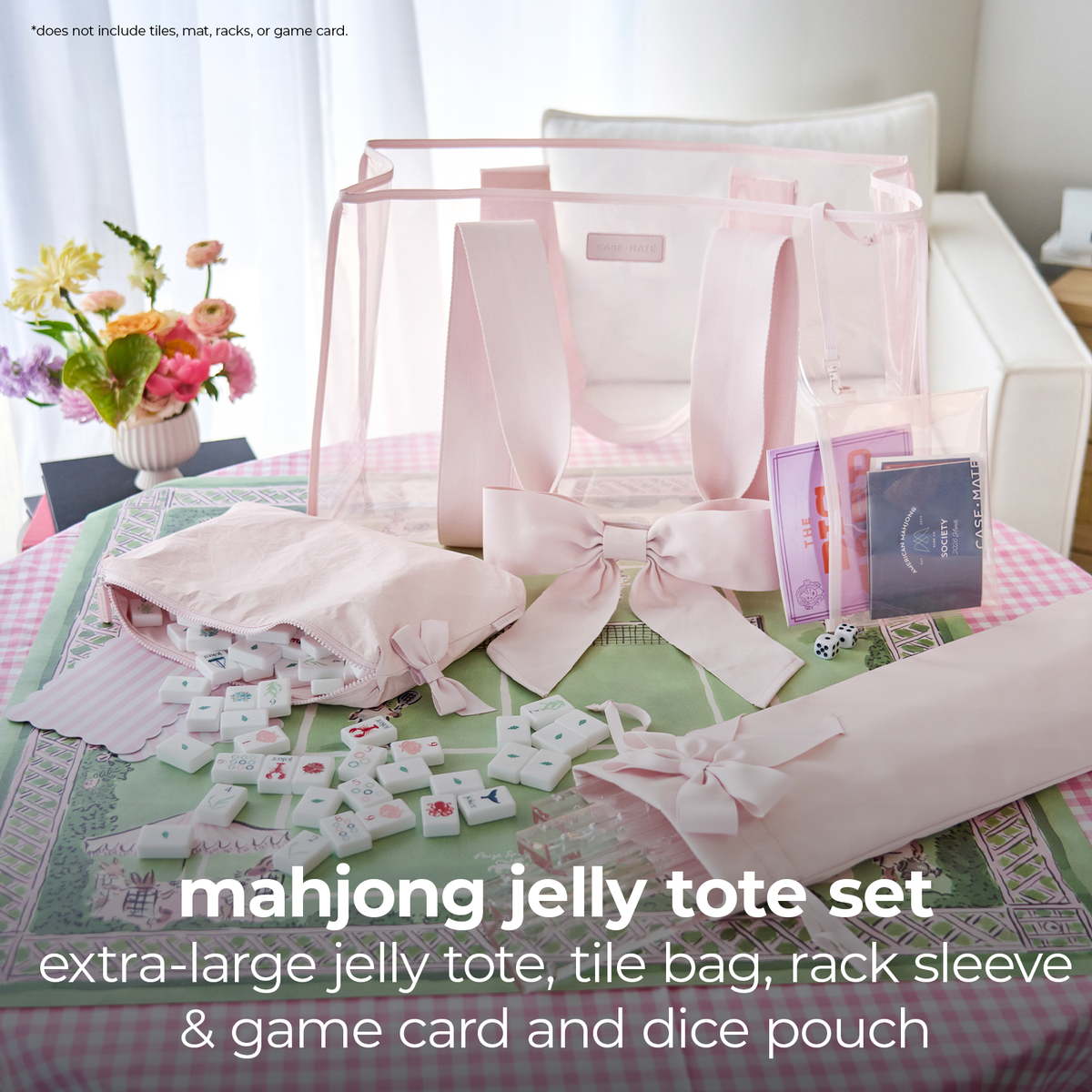 A pink mahjong jelly tote set displayed on a table, including a large translucent jelly tote bag, a folded pink bag, a pink ribbon-bow wrapped item, tile pouches, dice, and game cards. The set is arranged in a bright indoor setting with a sofa and flowers in the background.