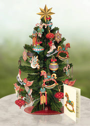 Decorative Christmas tree with colorful ornaments and a star on top, against a light green background.