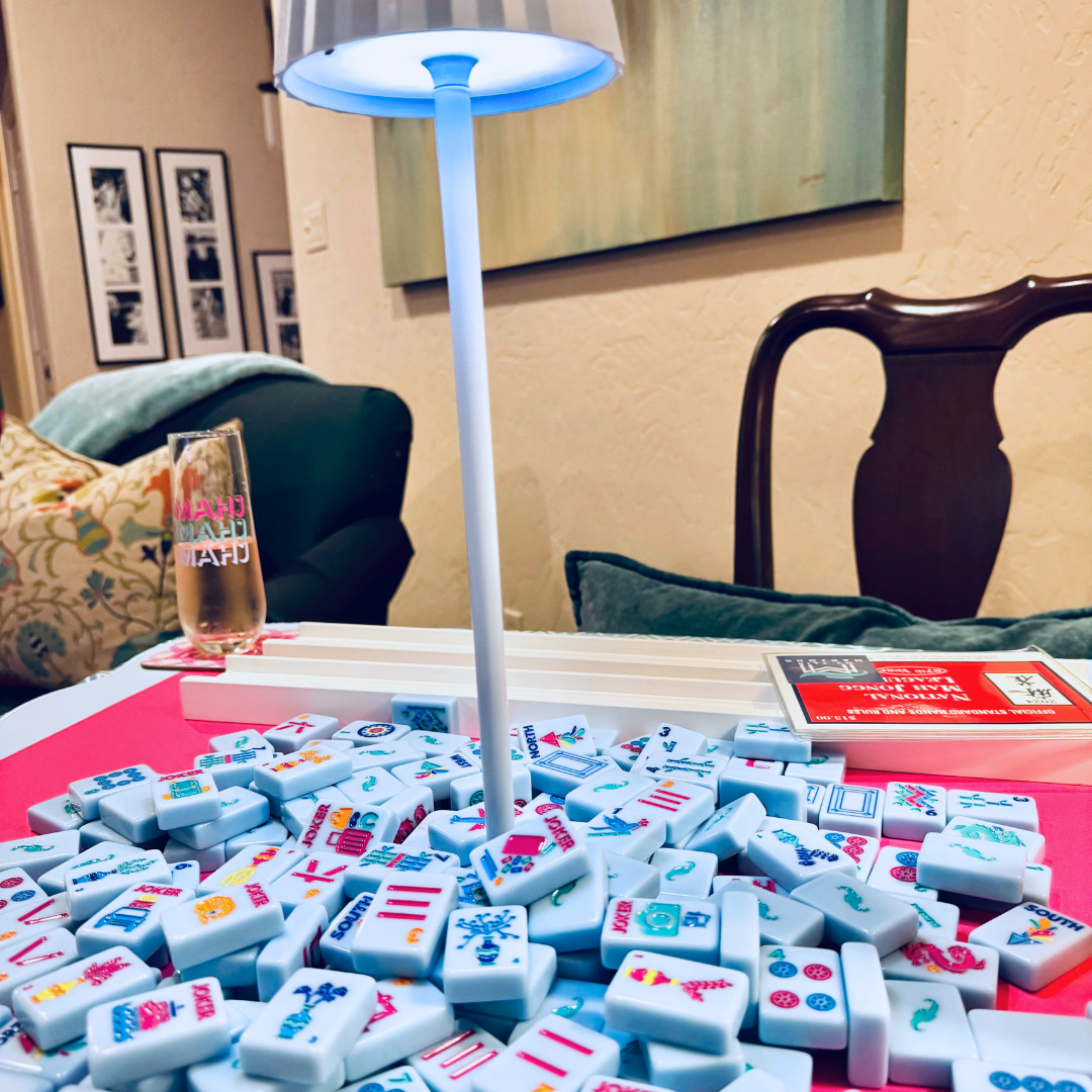 Mahjong tiles on a table with a lamp and glass in a room setting
