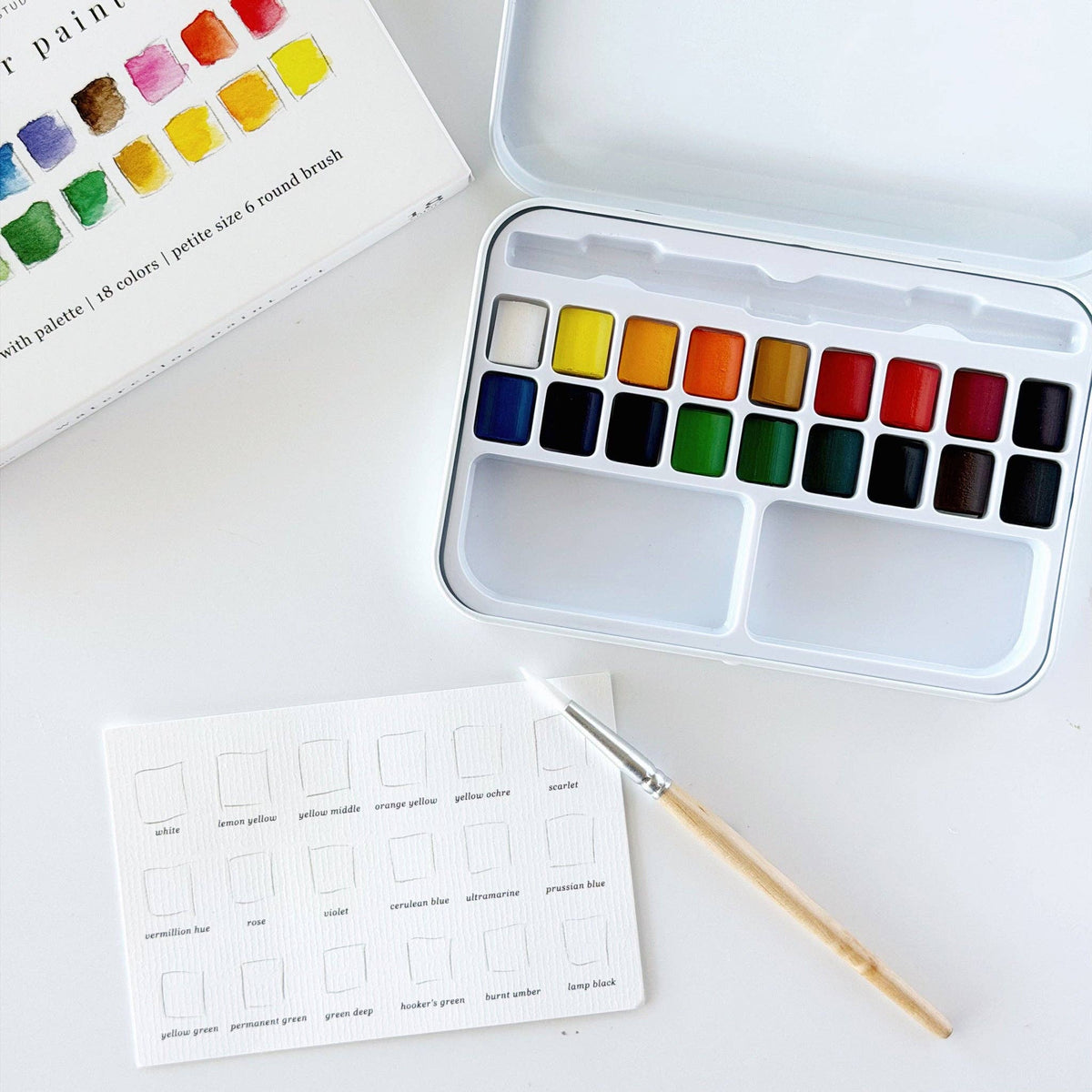 watercolor paint box with 18 colors and a paint brush on white background