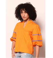 Person wearing an orange shirt with purple accents on a plain background