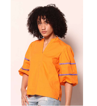 Person wearing an orange shirt with purple accents on a plain background