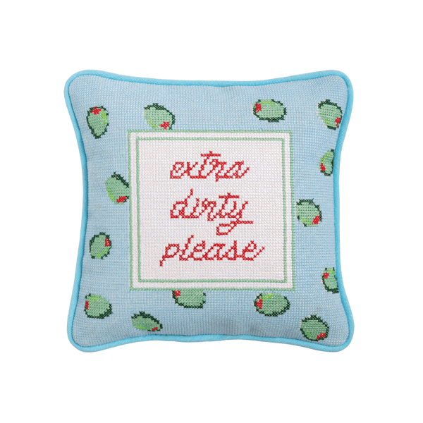 Decorative needlepoint pillow with olive patterns and text 'extra dirty please' on a light blue background