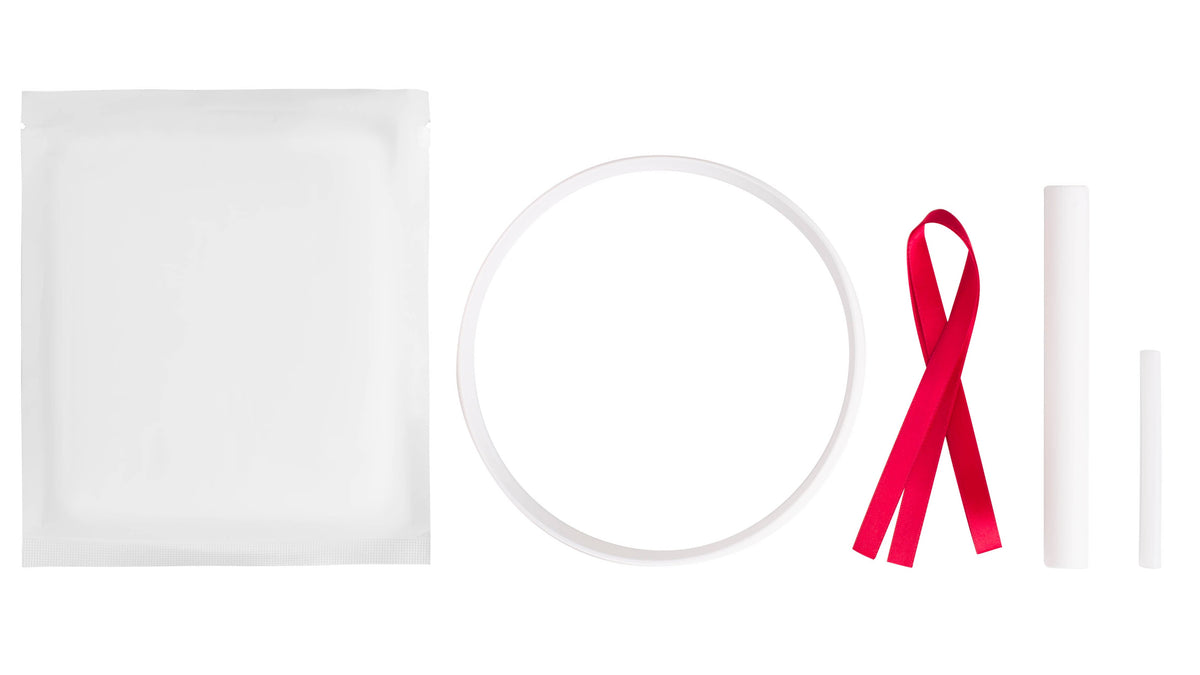A clean studio flat-lay of a white pet paw print kit including a red ribbon, and two white cylindrical tubes on a solid white background.