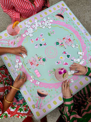 people paying mahjong on a Pink and green illustrated mahjong mat with colorful tile and cocktail cart design 
