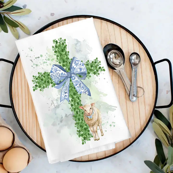 tea towel with boxwood cross and lamb design on background with tray and spoons