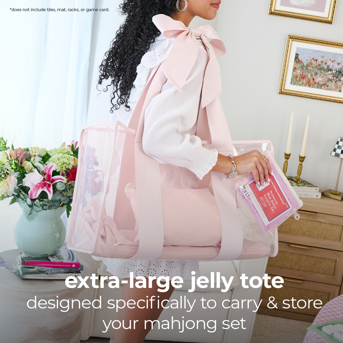 A woman in a white blouse carries a large pale pink translucent jelly tote bag with wide straps in a bright indoor room. The tote has clear side panels and a pink interior, and the text at the bottom reads 'extra-large jelly tote designed specifically to carry & store your mahjong set.