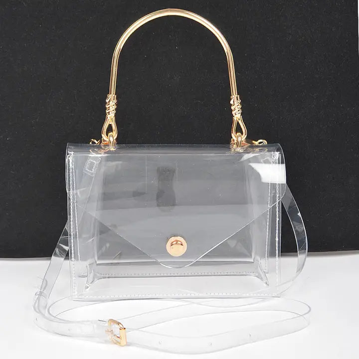 Transparent clear flap clutch with gold metal top handle and removable clear crossbody strap, gold ball button closure, front view on dark background