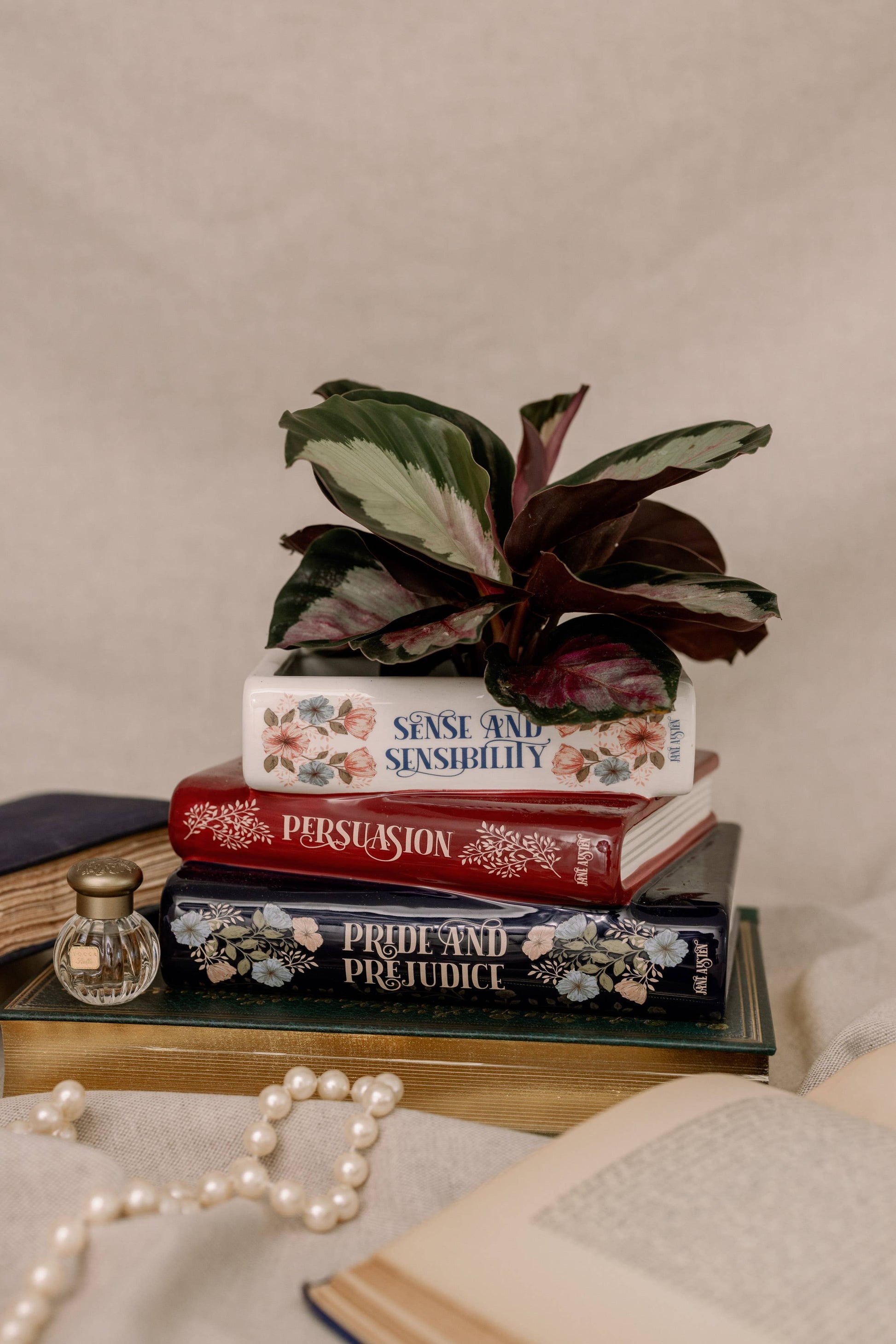 Steel Mill brand 3 stack book decorative vase/planter with Jane Austen titles on each one, withn a plant on a neutral background