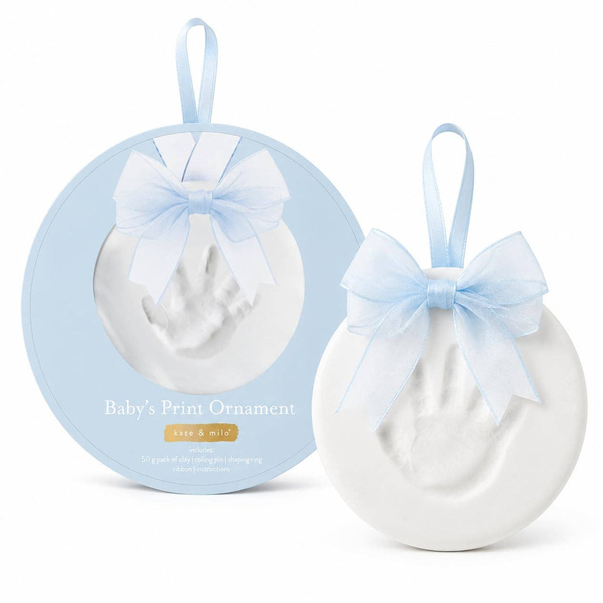 A baby footprint keepsake ornament shown both inside its round light blue presentation box and as the free ornament beside it. The ornament is white with a pale blue ribbon bow and hanging loop, and the box reads 'Baby's Print Ornament' with 'keep & mine' below.