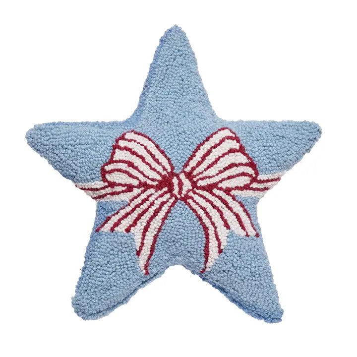 Star-shaped blue pillow with a red and white bow in the center on a white background