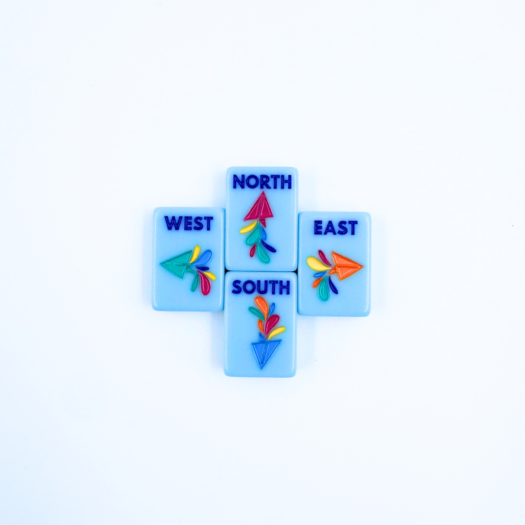 Set of four blue winds mahjong tiles with colorful arrows and text on a white background