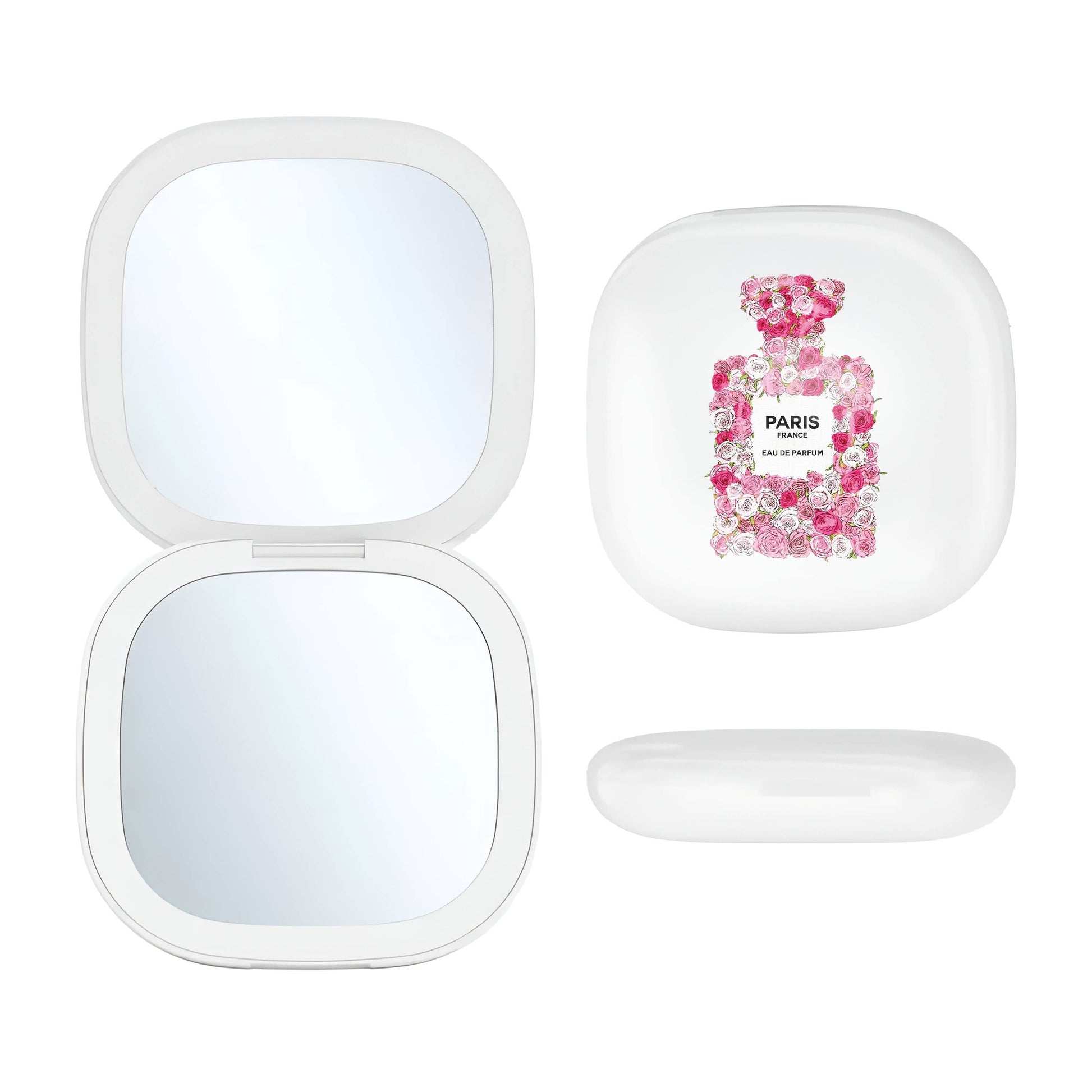 A Toss Designs Brand white compact mirror shown open on the left and closed on the right, with the closed lid featuring a pink floral perfume-bottle graphic and the word PARIS. A small white oval accessory piece is placed below the closed compact.