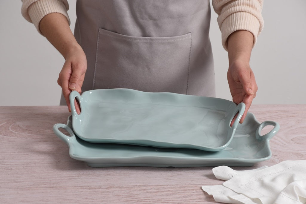 Person holding two light blue Pampa Bay Melamine trays on a wooden surface