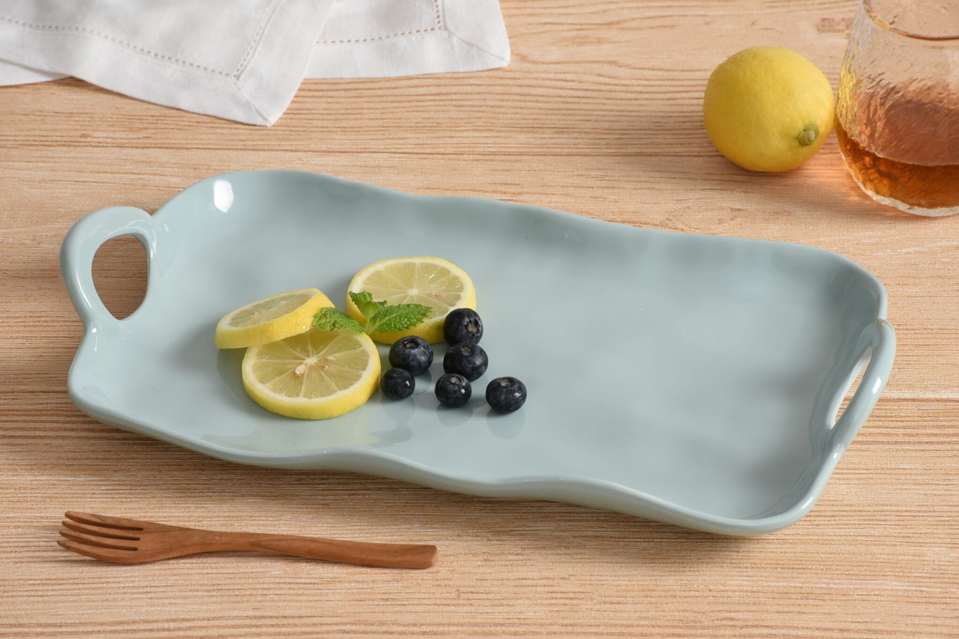 Pampa Bay Light blue melamine tray with lemon slices, blueberries, and a wooden fork on a wooden surface.