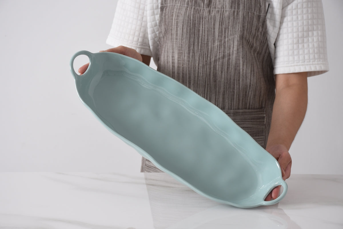 Person holding a light blue ceramic tray against a white background