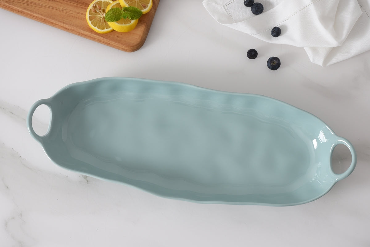 Light blue ceramic serving dish on a white surface with lemons and berries.