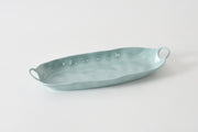 Light blue ceramic serving dish with handles on a white background