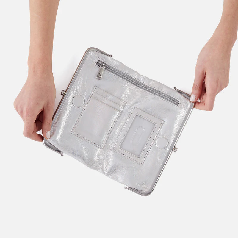 Silver clutch bag held by a person on a white background