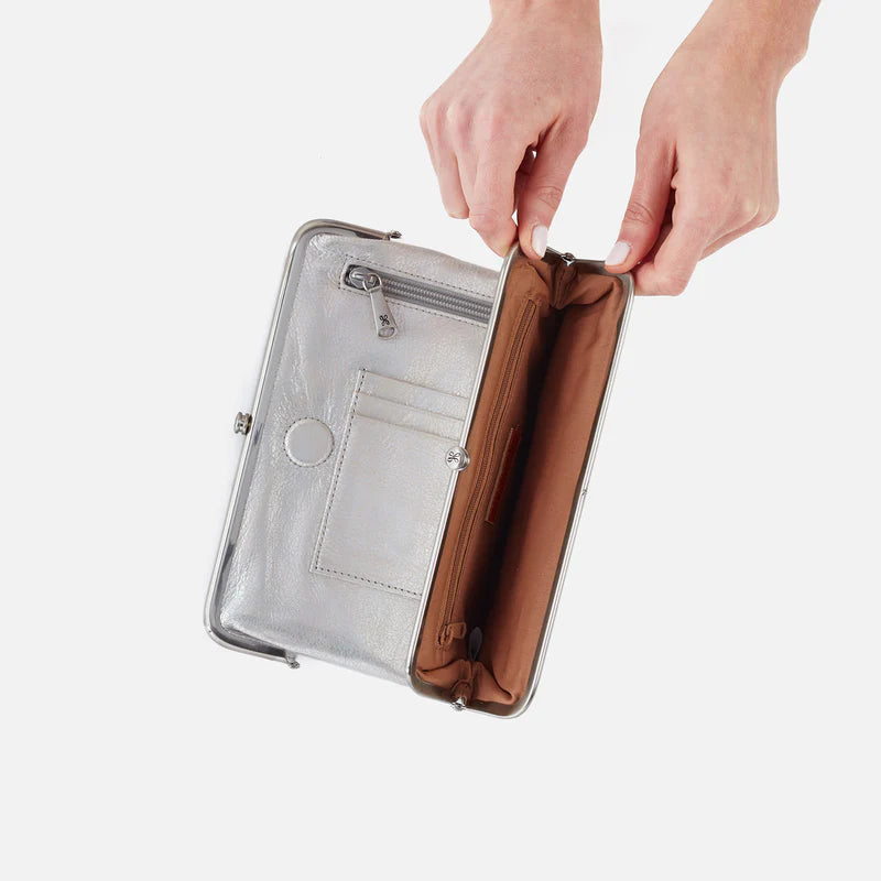 Person opening a silver clutch with a brown interior on a white background