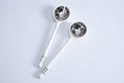 Two silver spoons with decorative handles on a light gray background