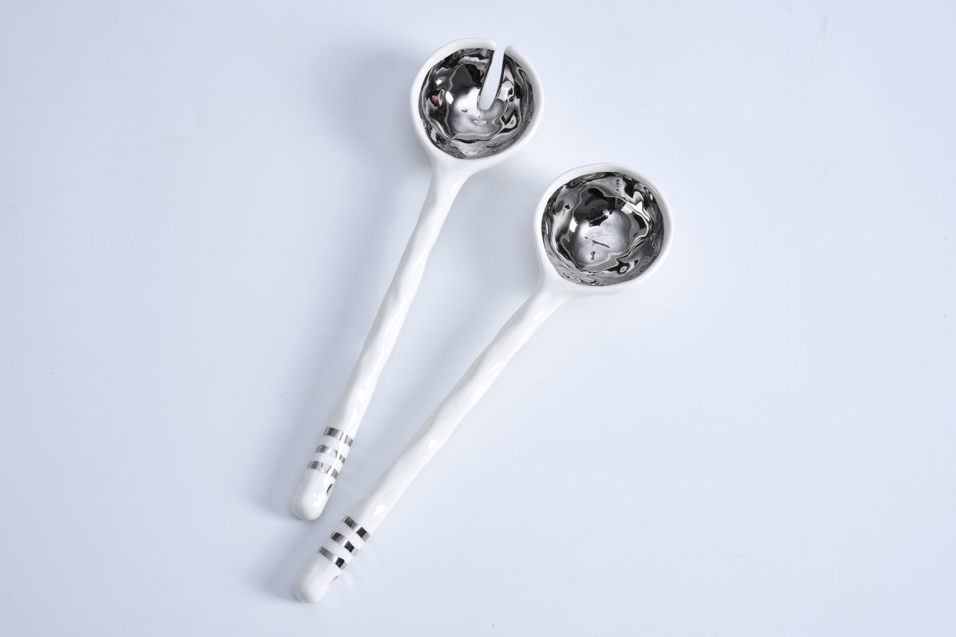 Two silver spoons with decorative handles on a light gray background