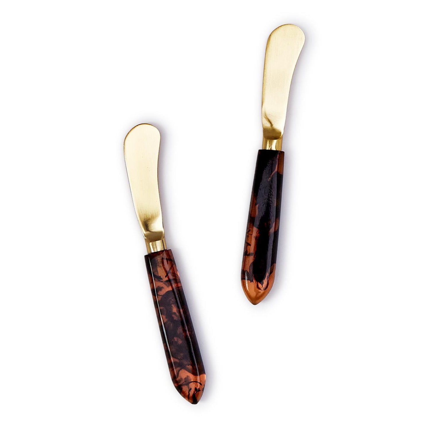 Two butter knives with tortoiseshell handles and gold blades on a white background