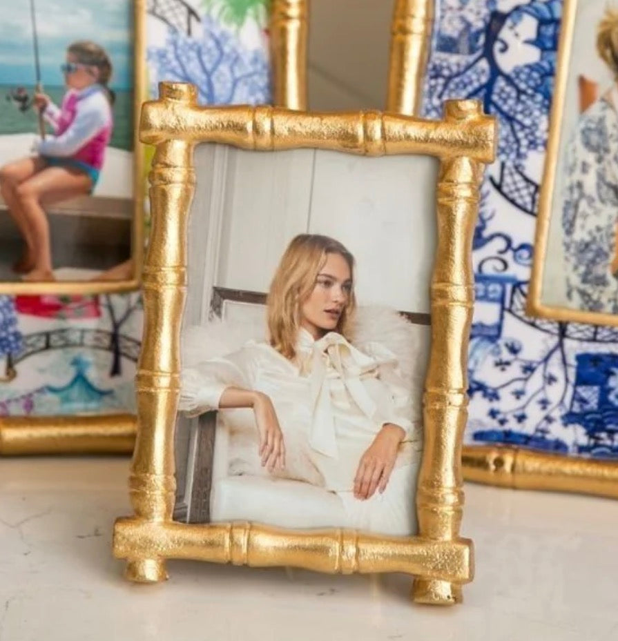 Gold bamboo-style picture frame with a photo of a woman inside, surrounded by other framed pictures.
