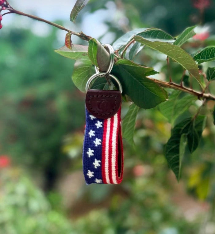 Needlepoint Keychain with American flag design hanging on a tree branch