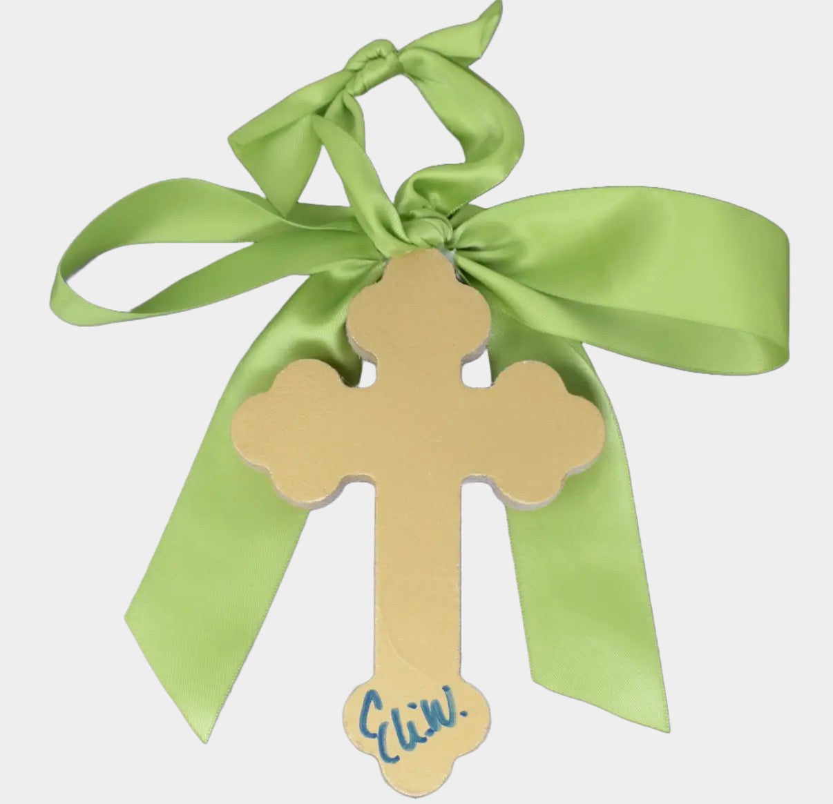 Gold cross with a green ribbon on a white background