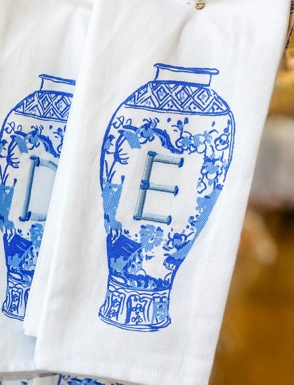 White fabric with blue decorative patterns and letter 'E' on a blurred background