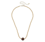 Gold necklace with a brown bead on a white background