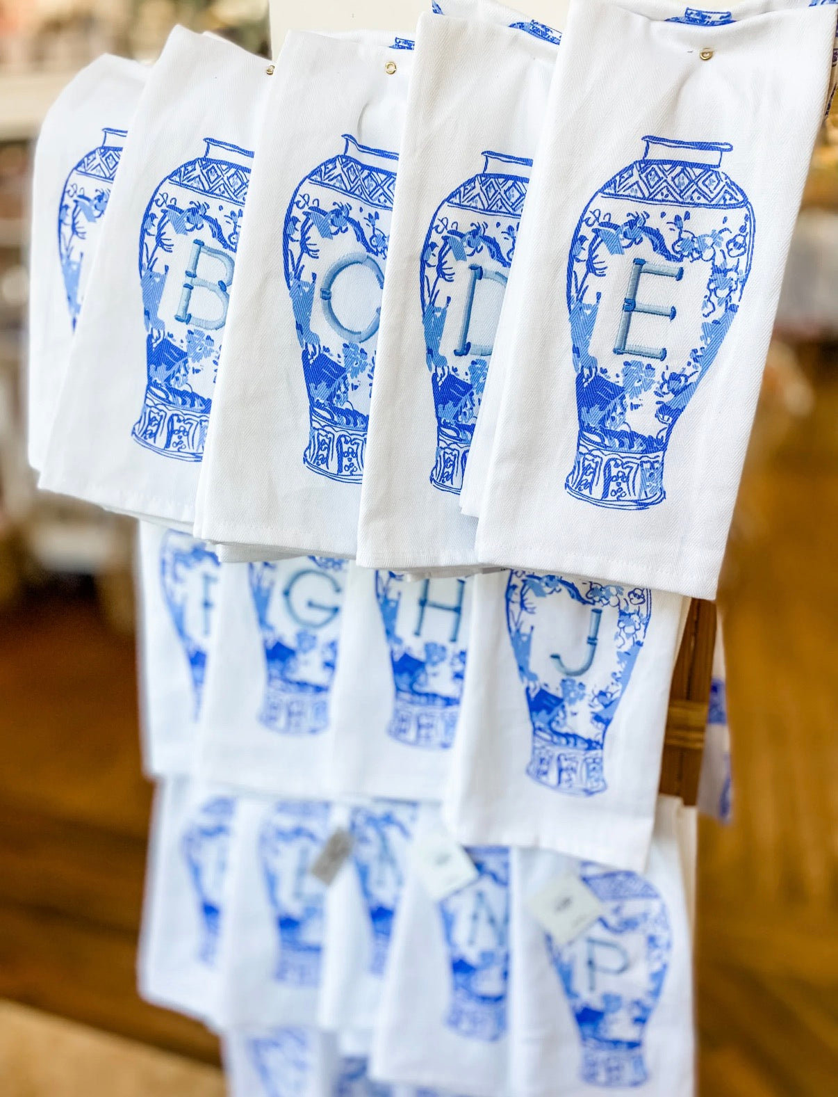 White towels with blue decorative patterns and letters hanging on a rack.