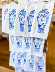 White towels with blue decorative patterns and letters hanging on a rack.