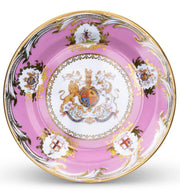 A 10-inch diameter decorative tin plate with a central floral and coat of arms design, surrounded by a pink background with gold accents.